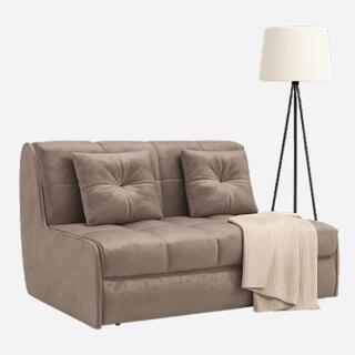 Компактный бежевый диван с двумя подушками и светлым пледом, рядом установлен напольный торшер на трёх ножках